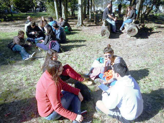 Um dia ensolarado com grupos de pessoas sentados na grama discutindo sobre eventos extremos.